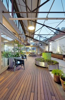 A 1960s Melbourne Warehouse Is Upcycled and Transformed Into an Energy-Efficient Family Home - Photo 10 of 11 - To overcome the waterproofing issues that come with having an internal courtyard, a hob was created around the perimeter and a new slab was constructed that drains water out to a central storm-water pit. The raised hob and slab are disguised by a new recycled timber deck that straddles the interior and exterior spaces, blurring the transition between the indoor and outdoor areas. Movable planter boxes made out of Cor-Ten steel were introduced to create a garden. 