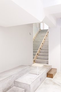 A Sleek Coffee Shop in Hong Kong With Beautiful, Minimalist Interiors - Photo 4 of 9 - The cement floor in front of the bar becomes a multi-tier platform seating area. A cement staircase leads customers to additional seating on the second floor. 
