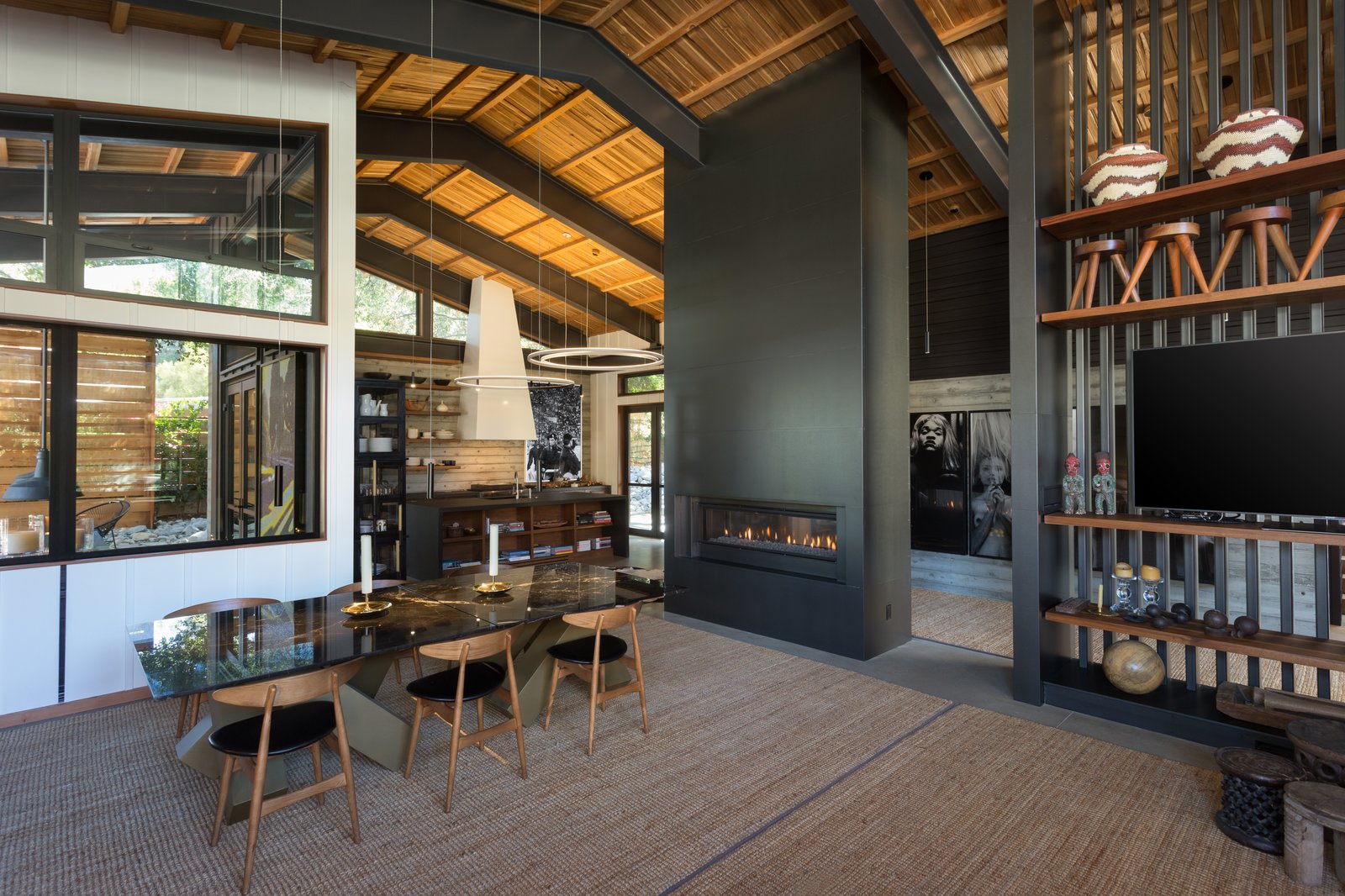 The interiors of the main home are elegant and airy, with a dark palette warmed by the use of natural wood. A dramatic fireplace is the centerpiece of the open plan great room.