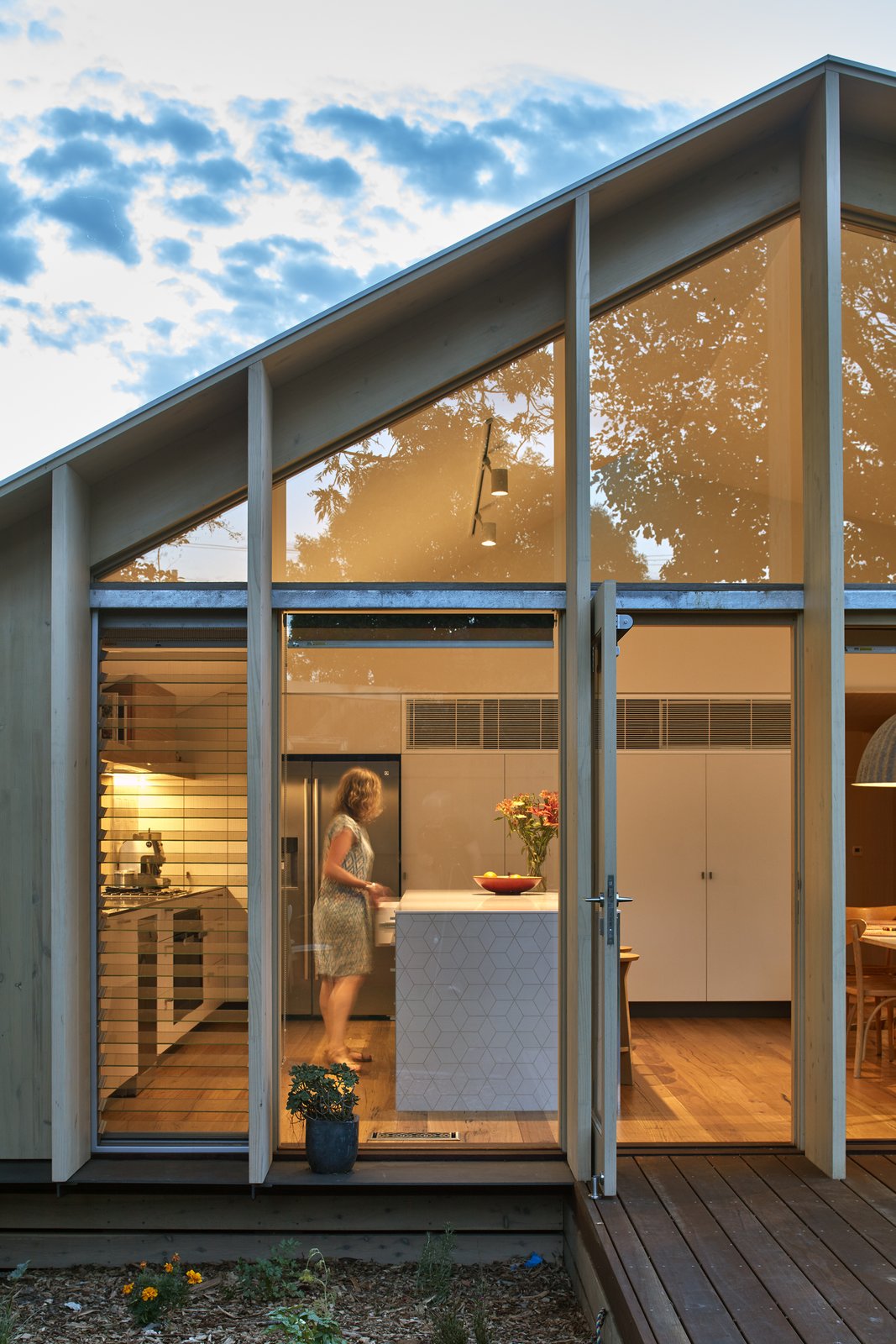 Floor-to-ceiling glass with sliding glass doors allow access to the decked outdoor space, covered by the roof's overhang.