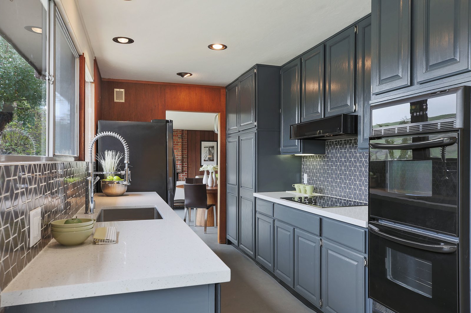 The updated kitchen features new quartz stone countertops, a tiled backsplash, and new stainless steel appliances.