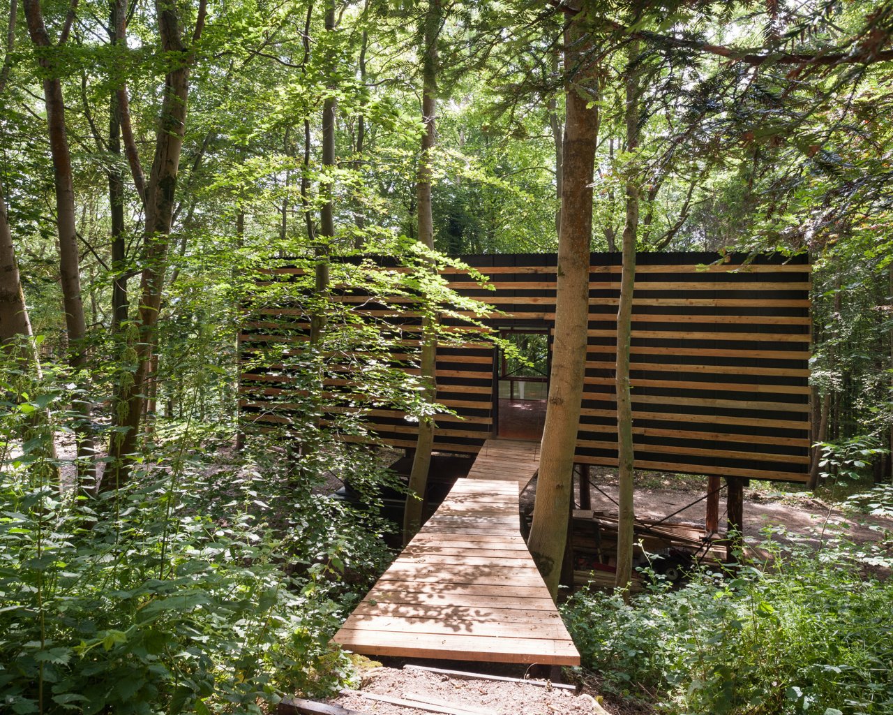 The studio is built on two floors—there is a 592-square-foot enclosed space accessed via a bridge from the slope which is above an open workshop.