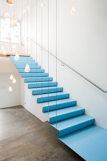A Creative Agency with a Modern, Open Workspace - Photo 2 of 9 - Floating stairs to the boardroom are framed by over forty porcelain 21 series pendants by Bocci.