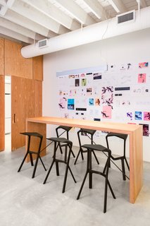 A Creative Agency with a Modern, Open Workspace - Photo 6 of 9 - The Douglas fir plywood bar table by Nico Spacecraft is flanked by Miura stools by Konstantin Grcic. 