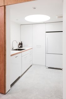 A Creative Agency with a Modern, Open Workspace - Photo 5 of 9 - The kitchen has a low ceiling with an inset circular skylight that creates a tubular glow.