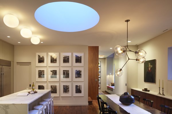 This photo shows the changing color temperature of the drum skylight. Here at dusk when the light turns a beautiful blue. The photo also highlights our use of multiple styles of architectural lighting: tape-in recessed LED downlight, surface mounted and pendent fixtures combine to create a warm modern environment. Photo of White Street Residence modern home
