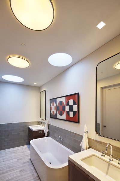 An overall photo of the master bath. As this room was part of the penthouse addition we were able to take advantage of the new roof by adding circular skylights which allow natural daylight into this interior space. Here the ceiling has a skylight above the far wall and also above the Duravit Happy D bathtub. You can lay back in the tub and look out to the sky. We added incandescent lighting with one of our all time favorite fixtures by Arne Jacobsen & Louis Poulsen. These fixtures also complement the circular skylights. The wall tile is the wonderful texture and color of Heath Ceramics - another great company Photo 7 of White Street Residence modern home