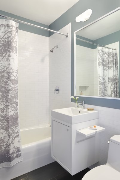 A side view of the Corian vanity with fold-up shelf. There is a routed pull that allows you to gain purchase to raise the shelf. The GFCI outlet, located in the niche, is accessed when in the up position & when not in use the shelf folds down and nests into the niche allowing it to sit flush with the vanity side. Photo 16 of Riverside Residence modern home