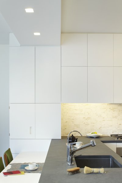 Often we have to work around awkward base building conditions. We removed an existing wall between the kitchen and living room to create a more modern open space - in doing so we needed to reroute a cold water supply line which we located in a new dropped soffit - to help make visual sense of this we aligned the leading edge of the Corian counter below with the soffit above. Photo 13 of Riverside Residence modern home