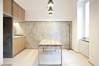 "It was supposed to be as naked as possible," says Alexandru Popescu, one of the members of R3Architetti who helped design and build the 3 Vaults apartment. "The furniture is absolutely included in the architecture; it's more like an indoor landscape instead of a typical open plan." The kitchen exemplifies their approach, with textured concrete walls contrasting with wood panels and salvaged industrial lighting. The table, custom built by R3Architetti, is made in part from pipes procured from one of their fathers, a plumber.