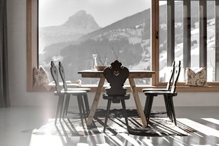 Find Sanctuary in This Chalet in the Italian Alps - Photo 5 of 12 - The kitchen and dining room enjoy panoramic mountain views. Local pine was hand-hewn for the flooring, windows, doors, and furniture throughout the residence.