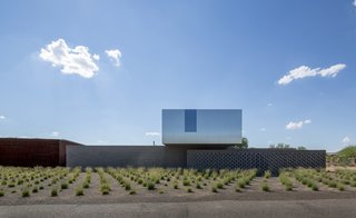 This Sleek Desert Home Seems to Melt Into the Sky - Photo 2 of 12 - Clad in stainless steel and coated glass, the upstairs volume seems to hover over the thick masonry walls and change colors with the shifting sky.