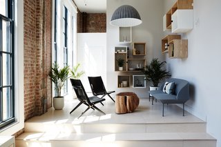 The library features a Muuto Oslo Sofa and Lassen Saxe Chairs. Exposed brick and generous windows are reminders of the warehouse setting. 