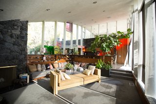 A realtor nicknamed the residence "The Rainbow House" for the colored glass that punctuates its arched walls. In the living room, where the panel was held, daylight casts a red streak into the kitchen and dinette area.