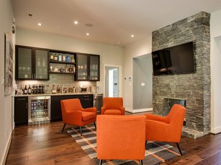 The kitchen flows into the living room, where a double-sided gas fireplace and a bluestone hearth provide a focal point. The granite top wet bar includes a KitchenAid beverage fridge and ice maker. A speaker system with volume control runs throughout the kitchen, living room, great room, master bedroom, and bathroom. 