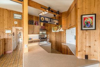 Settle in the Celebrated Sea Ranch For Under $2.9M - Photo 1 of 11 - Original wood paneling and tile flooring run throughout the house. The front entry leads into an integrated kitchen and dining space.
