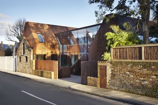 Weathered Steel Clads a $4.7M Home Near London’s Kew Gardens - Photo 1 of 10 - "Kew House was conceived as an interplay between the rustic exterior of weathering steel and retained stable wall and the refined, light interior," says Piercy, "the glazed circulation link revealing the contrast from inside and out." 