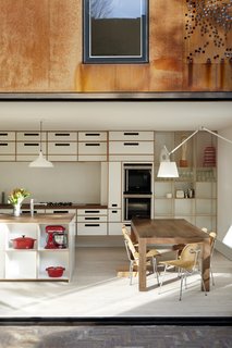 Weathered Steel Clads a $4.7M Home Near London’s Kew Gardens - Photo 5 of 10 - Birch ply cabinets with white melamine facings, walnut worktops, and integrated Siemens appliances create an airy workspace.