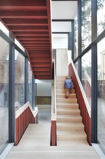 Weathered Steel Clads a $4.7M Home Near London’s Kew Gardens - Photo 6 of 10 - An exposed steel staircase in a glazed circulation link connects the two living wings.