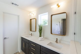 Ship Shape: An Austin Home With a Shipping Container Addition Asks $499K - Photo 5 of 9 - The master bathroom features brass mirrors, light fixtures, and hardware, taking visual cues from the brass accents found in the kitchen. 