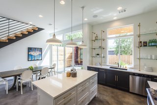 Ship Shape: An Austin Home With a Shipping Container Addition Asks $499K - Photo 2 of 9 - Rios describes Unit B as the more feminine of the two units. Here, black and white cabinets feature a glint of brass hardware. Made of brass galvanized pipe and glass, the shelves by the kitchen sink combine aesthetics and function.
