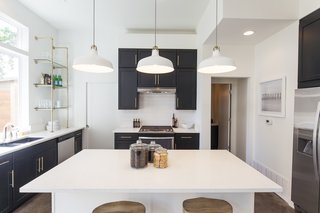 Ship Shape: An Austin Home With a Shipping Container Addition Asks $499K - Photo 3 of 9 - "I definitely wanted to give buyers a real sense of Austin," says Rios of the kitchen. "We have such beautiful restaurants and super unique design in our city. I feel like the shelving, high vent hood, gas stove, and double-stacked cabinets really expand on the volume of the home." 