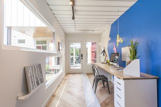 Ship Shape: An Austin Home With a Shipping Container Addition Asks $499K - Photo 9 of 9 - It's up to the homeowner to decide what to do with the additional 160 square feet; here, it's staged as an office. The shipping container features track lighting, wall sconces, a full-height cabinet to hang clothes, and a mini split air conditioner. The floors are a mix of engineered wood and hand-painted tile from Clay Imports. From inside the container, you can see through to the front of the house.