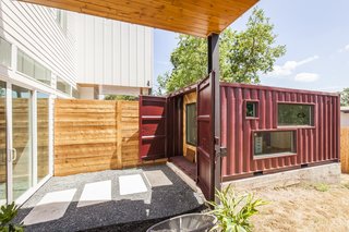 Ship Shape: An Austin Home With a Shipping Container Addition Asks $499K - Photo 7 of 9 - The two units in the duplex share a wall in the main house, so Rios continued the mirrored effect by placing the shipping containers side by side about 10 feet away from the home. Cut into the sides, the windows allow natural light to illuminate the shipping container and are designed to give parents a view of the kids playing in the backyard. 