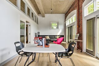 Towards the front of the house, where the original garage doors have been replaced by French doors and transom windows, is a multifunctional space with brick walls that currently functions as an office.