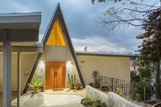 A Modified A-Frame Overlooking Los Angeles Starts at $699K - Photo 1 of 9 - Set back on a quiet street, the orange double doors on the triangular facade echo the warm glow of light streaming through the window.
