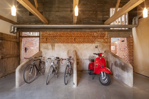 Modern home with storage room. The clients worked with Nossiter to preserve as many historical features as possible. The barn's cruciform plan arose from the model farm movement championed by original owner John Gurdon Esquire, who brought different farming functions under one roof. Here, what was once the old milking parlor now serves as bike and scooter storage. Photo 3 of Church Hill Barn
