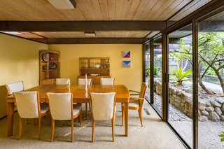 Snag This Midcentury Stunner in Southern California For $799K - Photo 7 of 10 - Homeowners can choose to eat in the dining room, pictured above, or bring their meal to a glass-encased lanai that looks out at the grassy backyard.