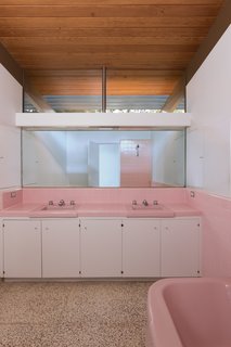 "The three original bathrooms were each designed in a different pastel color: pink, yellow, and blue," says Cole. These were mostly intact, though the homeowners reinstalled the colored Crane toilet in the master bath, pictured above. The restorers polished the original terrazzo flooring.
