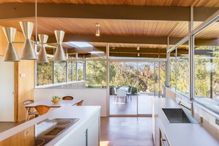 From the kitchen, you step out onto a side patio, which has an opening cut into the roof to allow sunlight to fall on a planter. The previous owners, in an attempt to remodel the house in the Spanish style, had gutted the kitchen. Eric Lamers rebuilt the space with cabinetry based on elevation drawings found in Neutra's "spec book," making changes according to practicality and building codes. Barbara Lamprecht helped the homeowners choose Porous Stone by Dunn Edwards for the paint. Believing that Neutra would have chosen modern fixtures, they installed a GE Monogram built-in refrigerator, wall oven, and induction cooktop. A KWC Suprimo faucet and Blanco sink complete the kitchen.