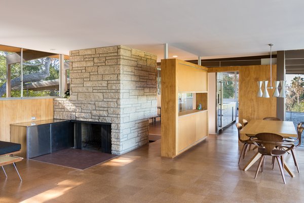 Nearly Slated For Destruction, a Restored Neutra in West Covina Asks $1.8M - Photo 4 of 8 - A stand-alone Texas shellstone fireplace divides the living and kitchen areas. The stainless steel wood storage boxes had been removed, so the current owners had it fabricated to Neutra's specifications. They also scraped off the "popcorn" or "cottage cheese" ceilings and went so far as to hunt down Schlage Plymouth door knobs and locks in bronze. Under Lamers' direction, a team of carpenters sanded each ceiling board, custom-milling and replacing about 20 percent that were beyond repair, and removed dark stain from the birch wall paneling. 