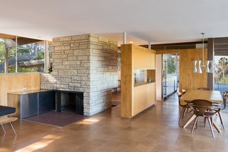 A stand-alone Texas shellstone fireplace divides the living and kitchen areas. The stainless steel wood storage boxes had been removed, so the current owners had it fabricated to Neutra's specifications. They also scraped off the "popcorn" or "cottage cheese" ceilings and went so far as to hunt down Schlage Plymouth door knobs and locks in bronze. Under Lamers' direction, a team of carpenters sanded each ceiling board, custom-milling and replacing about 20 percent that were beyond repair, and removed dark stain from the birch wall paneling. 