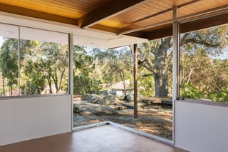 Situated on the eastern end of the residence, the master bedroom boasts a mitered glass corner window that overlooks a koi pond and a Live Oak tree. 