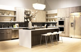 Signature Kitchen Suite’s Modern Pavilion Shines at KBIS - Photo 2 of 7 - The Signature Kitchen Suite Cooking Demonstration Kitchen features maple wood cabinetry by Green Forest Cabinetry, Porcelain White countertops by LG Hausys, and a Virginia Tile backsplash by Lunada Bay. A West Elm chandelier hangs over the island, adding a touch of drama.