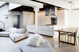 The minimalist, open kitchen was built into freestanding millwork walls. Valgora strove to layer design elements from the 19th, 20th, and 21st centuries. "Old growth wooden beams and angled timber columns from 1869 are exposed with riveted steel columns and tangles of pipes and infrastructure from the 1920s conversion to a factory," he points out. A modular On the Rocks sofa by designer Francesco Binfare breaks up the space and transitions into the living room.