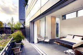 An expansive sliding glass door retracts into the zinc facade, opening up the master suite to a garden terrace with restored historic handrails. This echoes a 15-foot Corian wall that transforms a children's bedroom into an entertainment space, allowing flexibility and anticipating the time when the boys leave for college. 