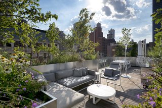 Connected by an exterior stone staircase, the rooftop level offers seating and dining areas and an outdoor kitchen.