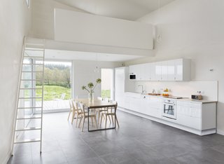 A sleek, minimal kitchen with lacquered MDF cabinets provides a glossy contrast to the unpainted walls.