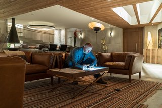 Here’s How Hollywood Builds a Malibu Dream Home—on a Vancouver Soundstage - Photo 4 of 10 - Real cedar planks line the ceilings. Novotny works in the television area, which features Sorensen Leather Chairs by Restoration Hardware, the Torme Floor Lamp by Mr. Brown, and IKEA rugs.