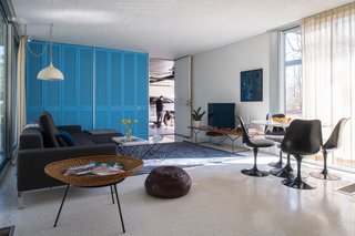 A Rare Midcentury Prefab Looks Just Like it Did in 1958—Down to the Knoll and Paul McCobb Interiors - Photo 9 of 13 - A Bertoia Bench in white oak supports the TV in the family room, while a 50th anniversary-edition Saarinen Tulip Table and Chairs provide a dark contrast to the cheery interiors. The vintage spun aluminum light fixture is also original to the house. Notice how the Knoll curtain, when open, can be neatly tucked into a nook beside the blue closets.