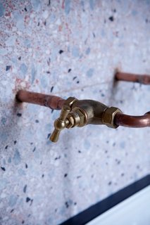 11 Examples of How to Incorporate Traditional Building Materials Into Your Modern Home - Photo 8 of 12 - Copper piping extends out from the wall to become the faucets in a terrazzo-covered bathroom in Paris, France.