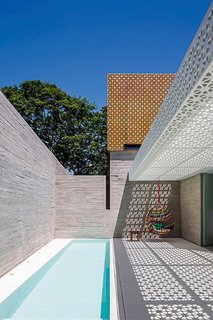 5 Striking Designs That Use Perforated Cement Breeze-Blocks in Interesting Ways - Photo 5 of 10 - Located in São Paulo, Brazil, this outdoor space designed by Figueroa Arq employs both poured-in-place concrete and perforated concrete blocks to produce a strong contrast between the white-and-orange lattice of the blocks and the solid walls of the gray concrete. <span style="color: rgb(204, 204, 204); font-size: 13px;">Photo by Leonardo Finotti</span>