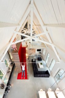 Traditional Churches Become Modern Homes - Photo 2 of 10 - Located in Harrlo, The Netherlands, this home was once the Dutch Reformed Evangelism Building before being transformed by Leijh Kappelhoff Seckel van den Dobbelsteen architecten. The new design includes a bedroom and bathroom loft with modern features and furnishings paired with many of the original details, including the wood roof and the arched stained glass windows.