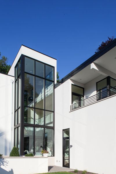 Outside, strong roof overhangs accentuate the horizontality of the modern white stucco facades and natural limestone provides a counterpoint to the smooth white stucco. The limestone not only grounds the house but serves as a symbolic link to the couple’s previous residence, which also featured similar stonework. Photo 6 of Woodland Road Residence modern home