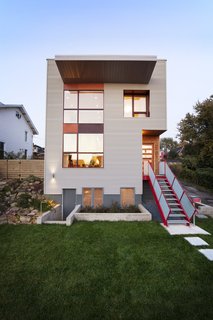 Slim Is in For These 10 Skinny Homes - Photo 7 of 10 - The structure features exterior materials that directly illustrate the dichotomy between Lawrenceville’s industrial heritage and Lola House’s residential nature. Here, corrugated metal siding is balanced with the warmth and softness of cedar siding, which was selected to emphasize the vertical circulation of the home. Red accents of cement board and steel bring a modern touch to the building’s exterior.