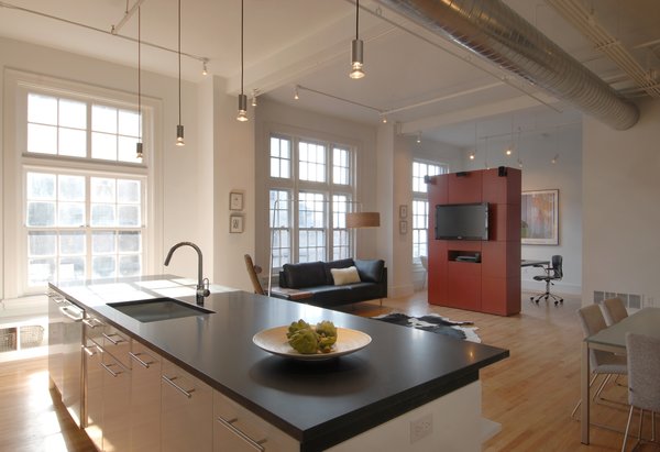 Punctuating the white palette and historic building details as pops of modern design and color are two freestanding volumes, clad in custom red panels and placed so as to define specific living spaces within the long, rectangular loft. These “cubes” separate public zones from private and create rooms without walls or doors, while appearing to float under the 12-foot-high ceilings. Photo 2 of Y Lofts modern home